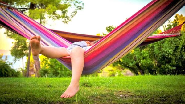 Child chilling on a hammock dangling feet